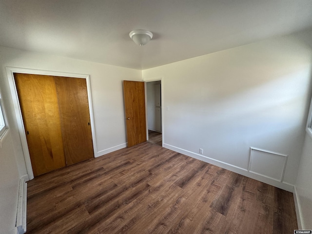 unfurnished bedroom with a closet, baseboards, and wood finished floors