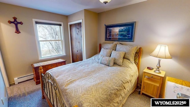 bedroom with a closet, a baseboard heating unit, and carpet flooring