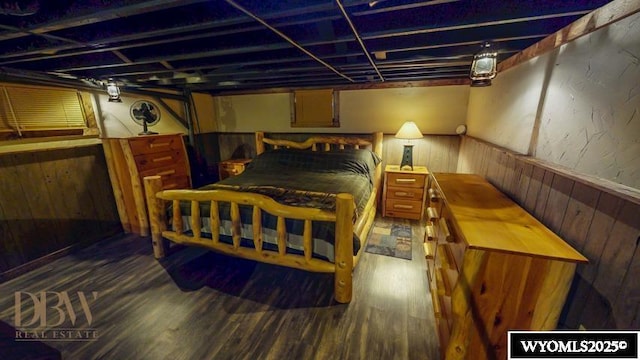 bedroom featuring wood finished floors, wooden walls, and a wainscoted wall