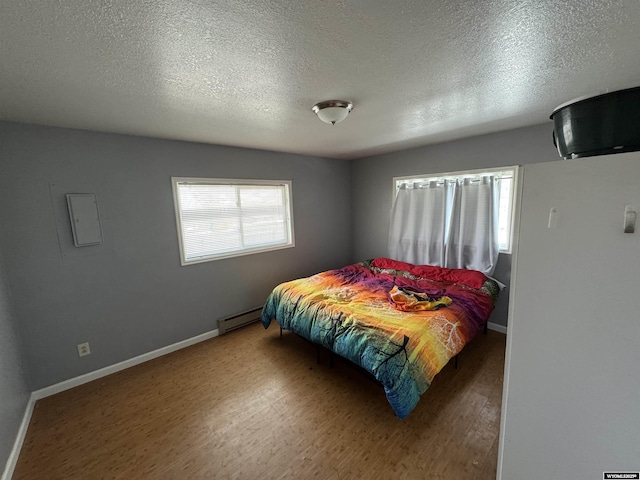 104 Brinton Rd, Lyman, WY 82937 - bedroom featuring baseboard heating, a textured ceiling, baseboards, and wood finished floors