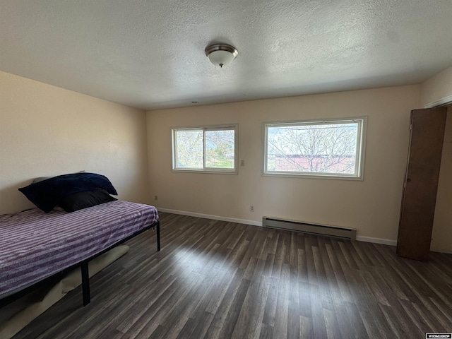 104 Brinton Rd, Lyman, WY 82937 - bedroom featuring baseboard heating, wood finished floors, baseboards, and a textured ceiling