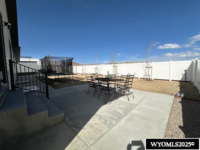109 Chardonnay, Rock Springs, WY 82901 - view of patio featuring a fenced backyard, a trampoline, and outdoor dining space