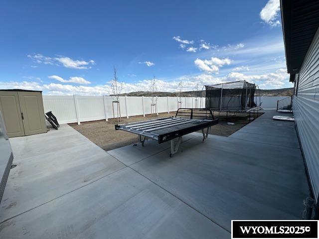 109 Chardonnay, Rock Springs, WY 82901 - view of patio / terrace with a fenced backyard, a trampoline, an outbuilding, and a storage shed