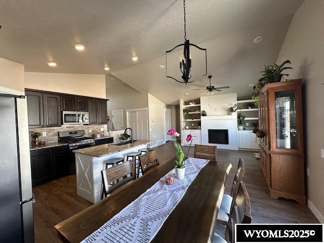 109 Chardonnay, Rock Springs, WY 82901 - dining area featuring a fireplace, baseboards, dark wood finished floors, ceiling fan with notable chandelier, and vaulted ceiling