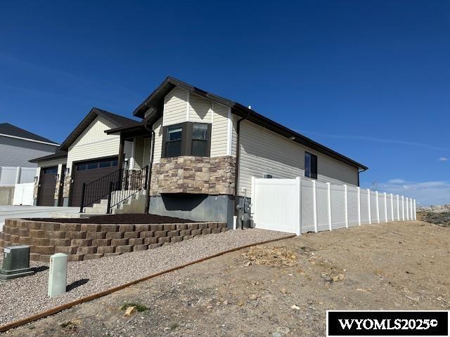 109 Chardonnay, Rock Springs, WY 82901 - view of home's exterior featuring an attached garage, central AC unit, fence, and stone siding