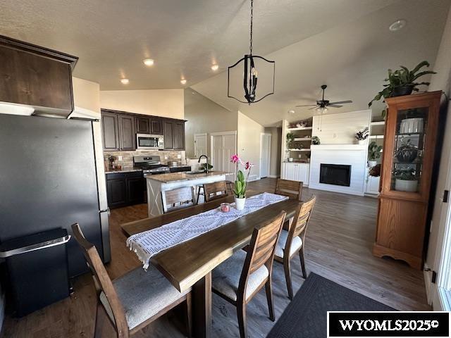109 Chardonnay, Rock Springs, WY 82901 - dining area featuring a fireplace, built in shelves, ceiling fan with notable chandelier, dark wood-type flooring, and vaulted ceiling