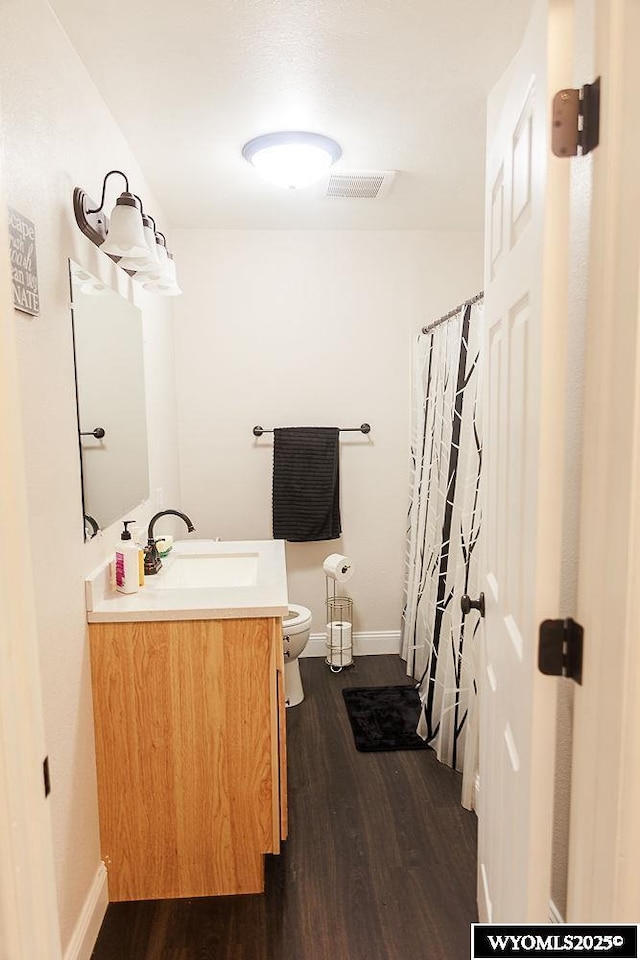 full bath with vanity, toilet, baseboards, wood finished floors, and visible vents