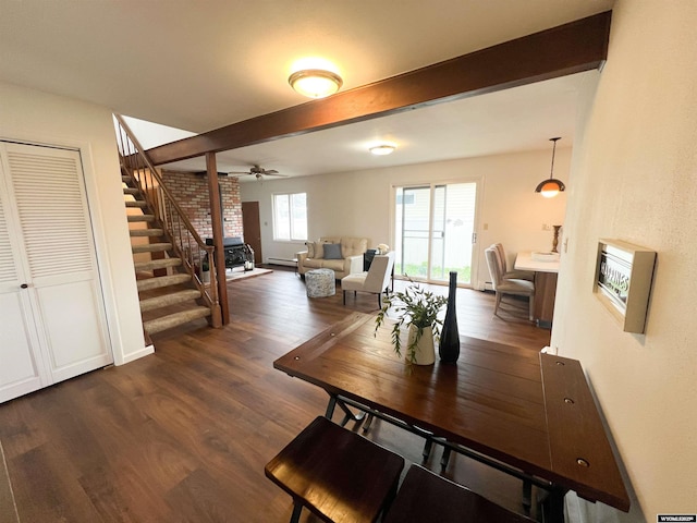 dining space featuring dark wood-style flooring, ceiling fan, beam ceiling, and stairway