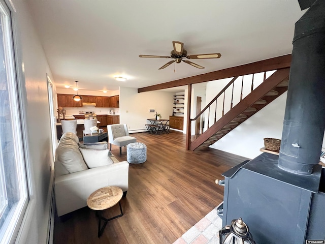 living room with stairs, a ceiling fan, baseboard heating, and dark wood-type flooring