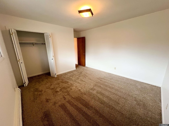 unfurnished bedroom featuring carpet flooring, baseboards, a baseboard heating unit, and a closet