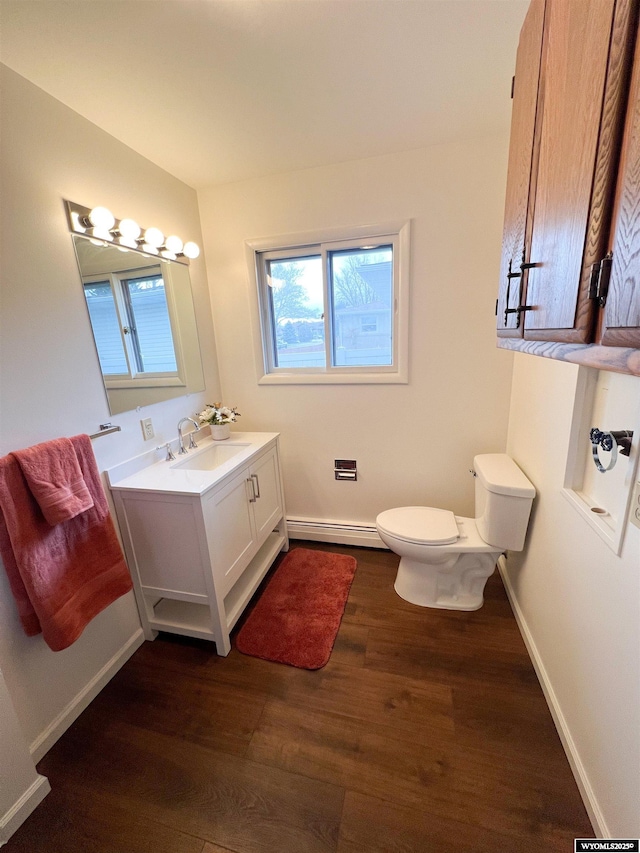 bathroom featuring vanity, wood finished floors, toilet, baseboards, and a baseboard heating unit