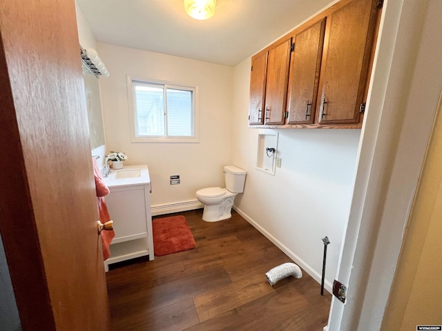 half bathroom featuring wood finished floors, vanity, a baseboard radiator, baseboards, and toilet
