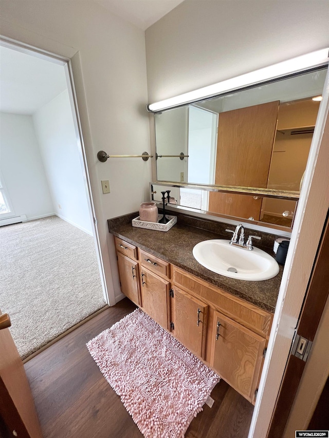bathroom with baseboard heating, a healthy amount of sunlight, wood finished floors, and vanity