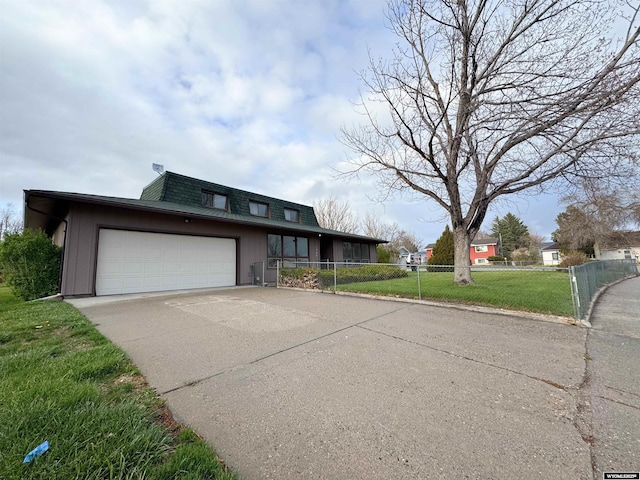 traditional home with fence, an attached garage, a front yard, concrete driveway, and mansard roof
