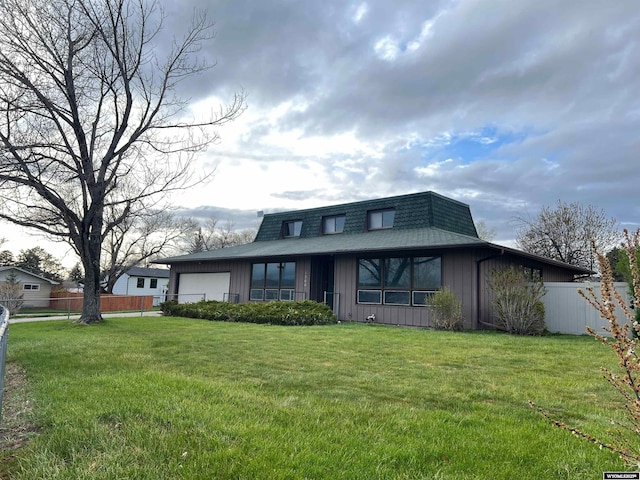 view of front of home featuring board and batten siding, a front yard, mansard roof, fence, and an attached garage