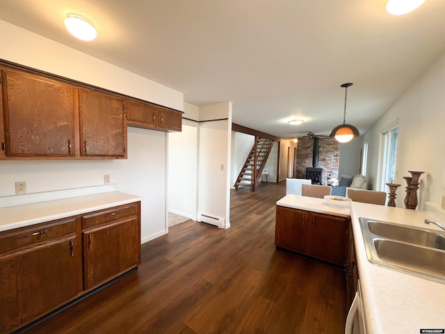 kitchen with a wood stove, dark wood finished floors, a sink, light countertops, and open floor plan