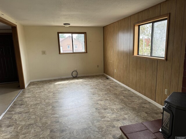 124 Railroad St, Lingle, WY 82223 - empty room with baseboards, a wood stove, and wood walls