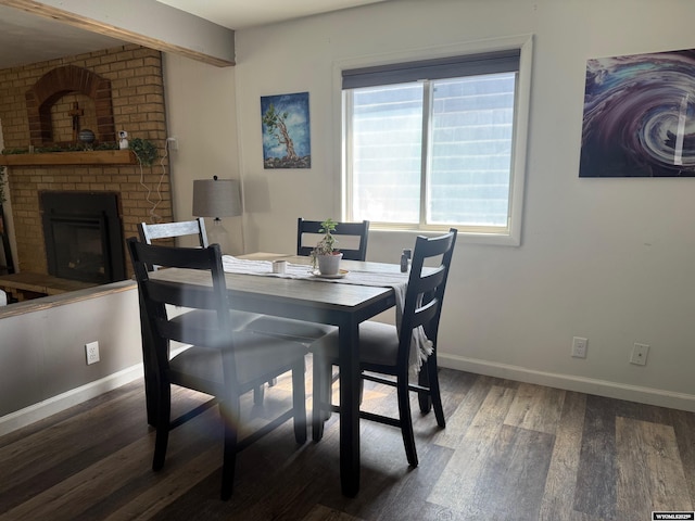 dining space with a brick fireplace, baseboards, and wood finished floors