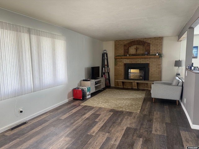 living room with baseboards, a fireplace, wood finished floors, and visible vents