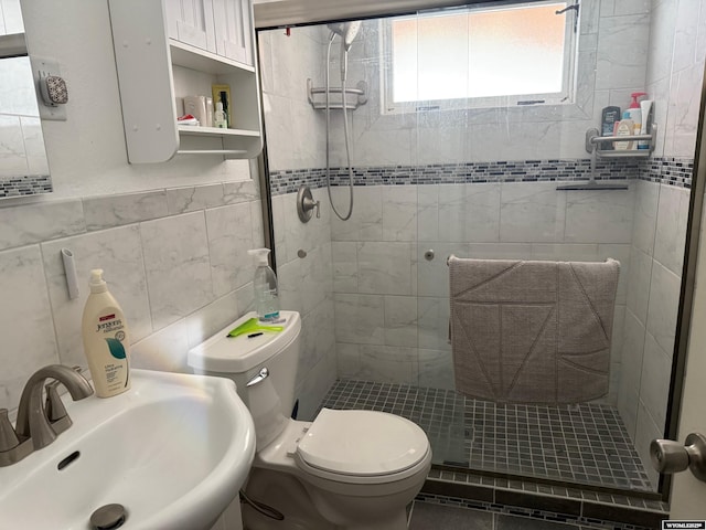 bathroom featuring a sink, toilet, and a shower stall