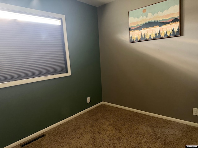 carpeted empty room featuring baseboards and visible vents