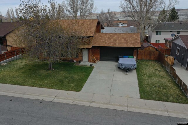 view of front of home with a shingled roof, driveway, and a front yard