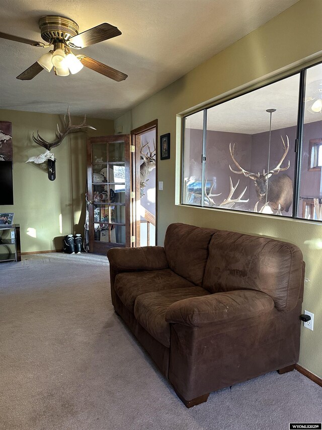 living area with a ceiling fan and carpet flooring
