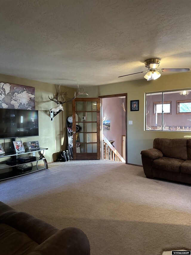 carpeted living area with a ceiling fan and a textured ceiling