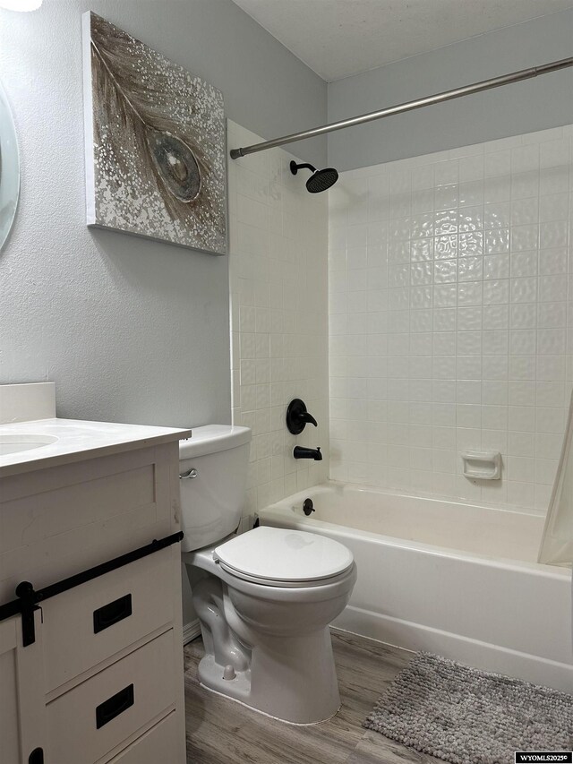 bathroom featuring vanity, washtub / shower combination, wood finished floors, and toilet
