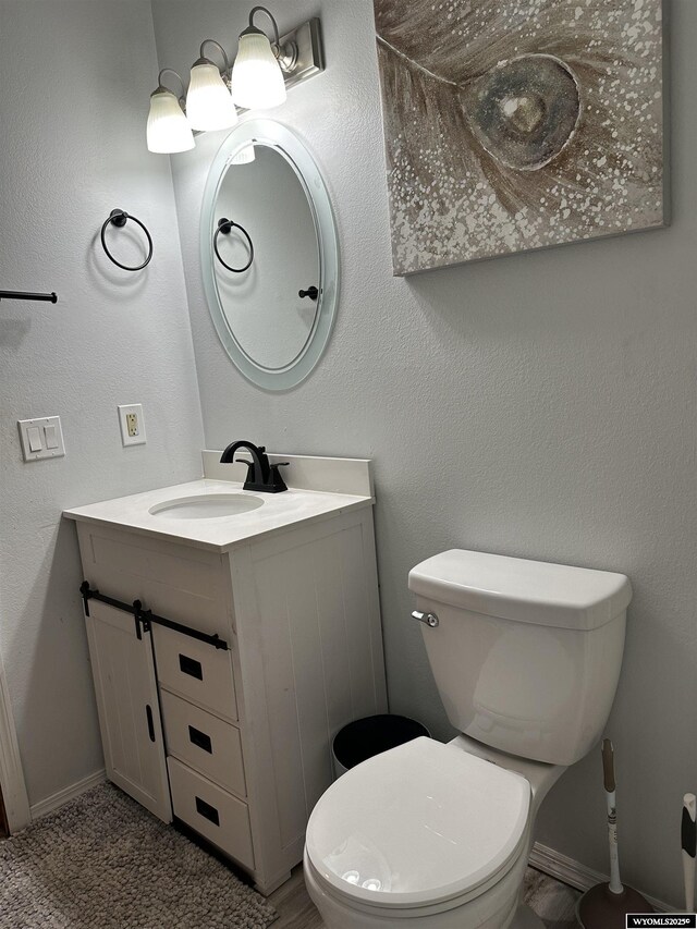 half bath with vanity, baseboards, and toilet