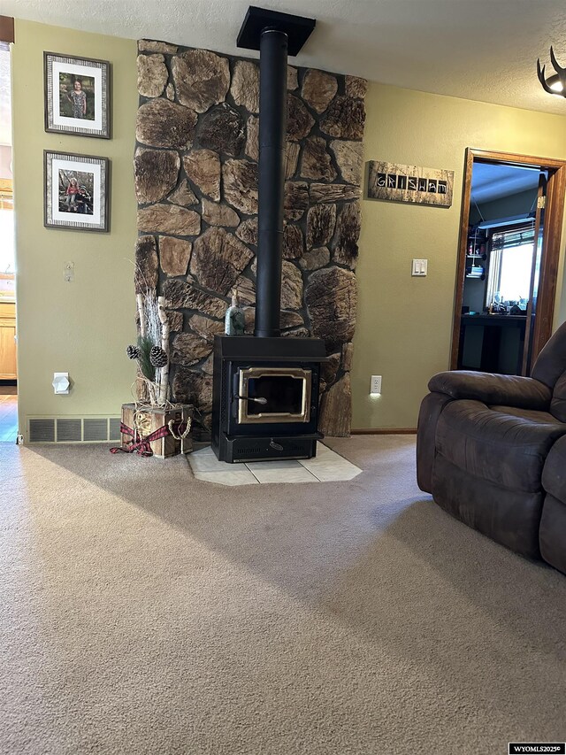 carpeted living area with visible vents and a wood stove