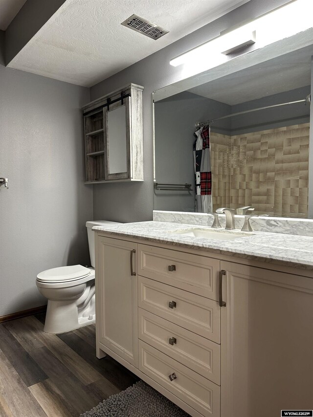 bathroom with visible vents, vanity, wood finished floors, curtained shower, and toilet