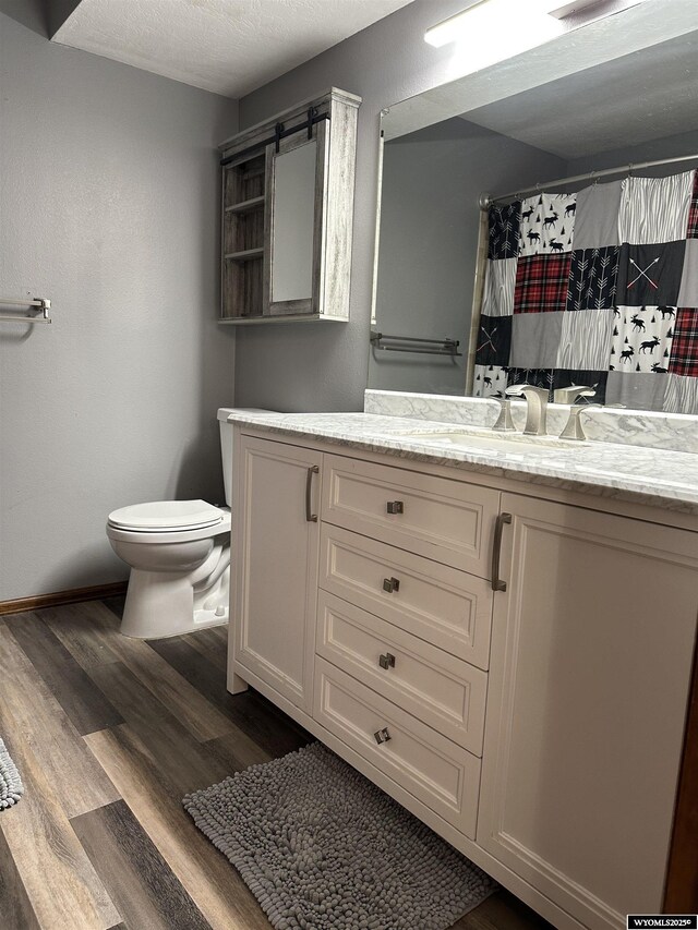 full bathroom featuring vanity, wood finished floors, curtained shower, toilet, and baseboards