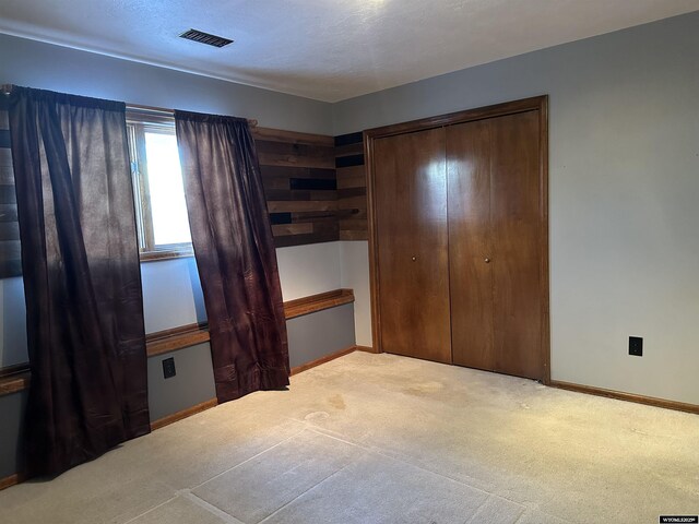 unfurnished bedroom with visible vents, carpet, baseboards, and a closet