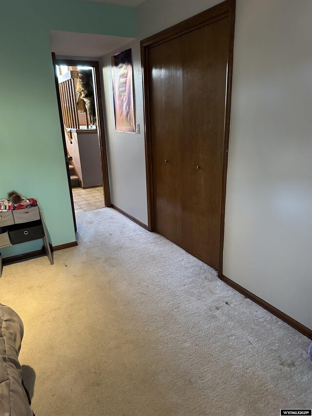 bedroom with baseboards, light colored carpet, and a closet