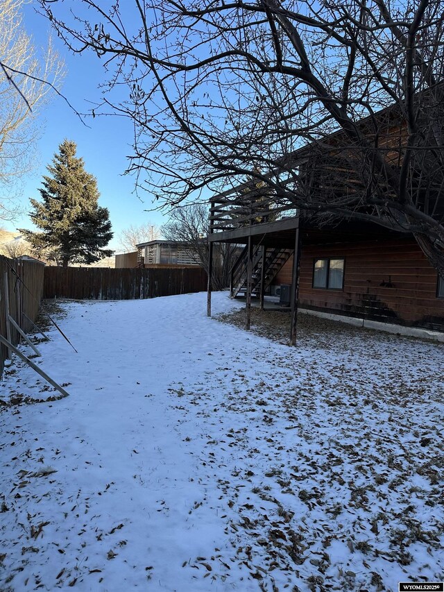 yard covered in snow with fence and stairs