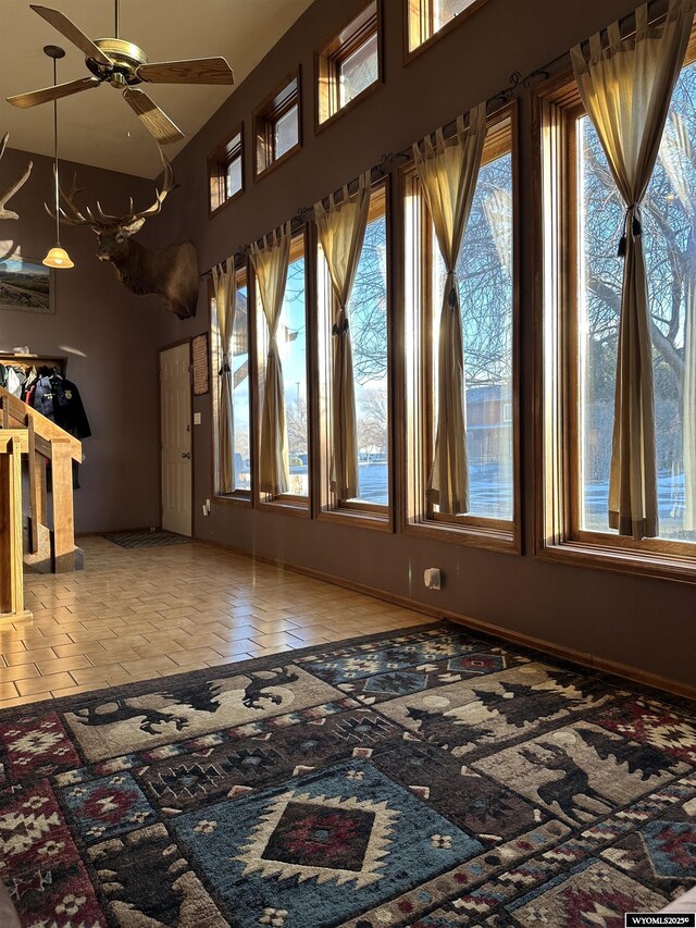 unfurnished living room featuring ceiling fan, a wealth of natural light, and a high ceiling