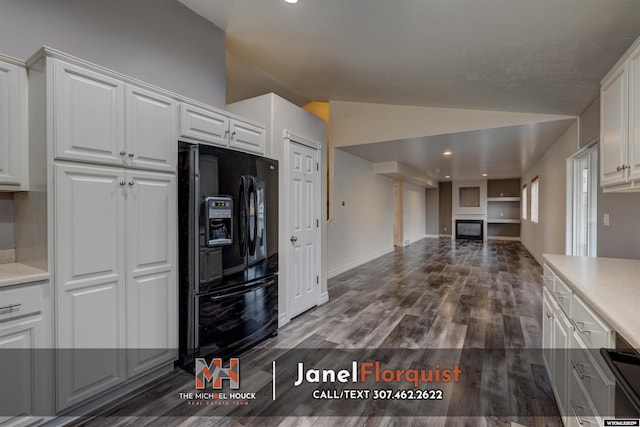 kitchen with black fridge with ice dispenser, lofted ceiling, a fireplace, light countertops, and white cabinetry