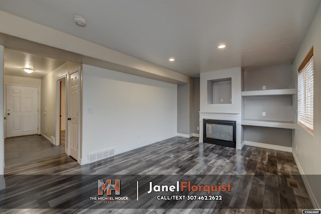 3507 Aspen Ln, Casper, WY 82604 - unfurnished living room featuring a glass covered fireplace, baseboards, dark wood-style floors, and visible vents