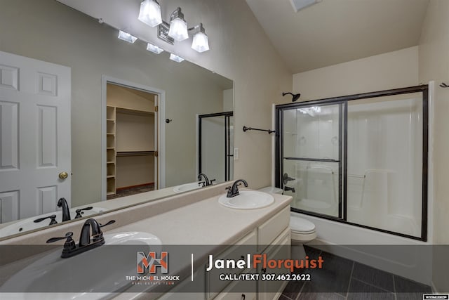 bathroom with a sink, double vanity, toilet, tile patterned floors, and bath / shower combo with glass door