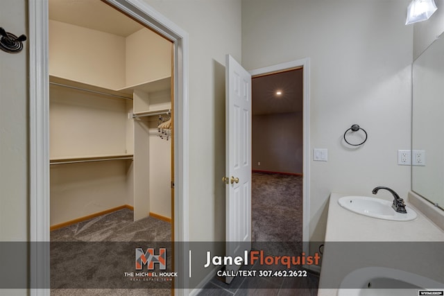 bathroom featuring baseboards, a spacious closet, and vanity