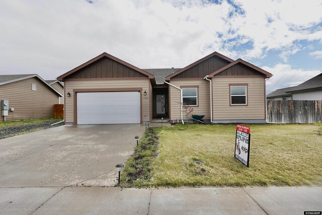 ranch-style house featuring board and batten siding, driveway, a front yard, a garage, and fence