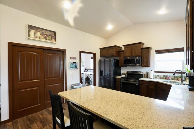kitchen featuring dark brown cabinetry, washer and dryer, a sink, black appliances, and vaulted ceiling