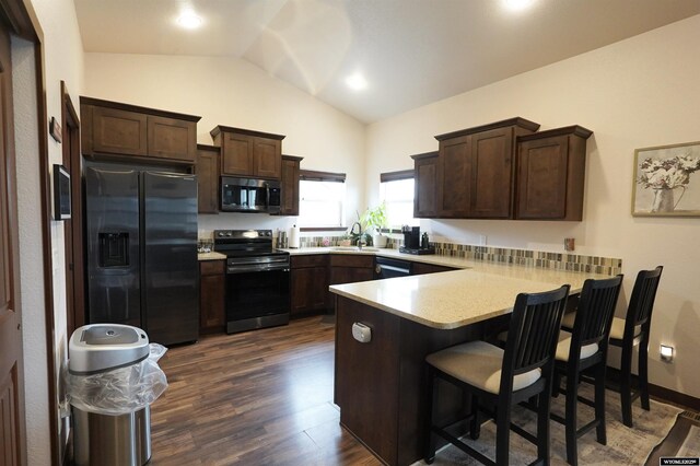 kitchen featuring a peninsula, lofted ceiling, dark brown cabinetry, light countertops, and black appliances
