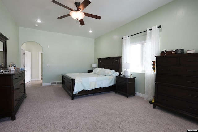 bedroom featuring ceiling fan, light carpet, arched walkways, baseboards, and visible vents