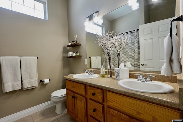full bath with double vanity, a sink, tile patterned floors, and toilet