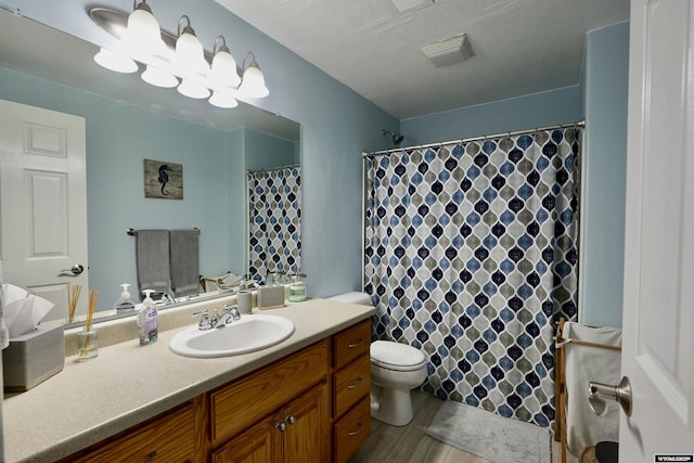 full bathroom with visible vents, curtained shower, wood finished floors, vanity, and toilet