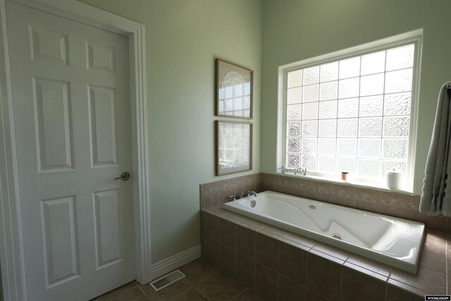 bathroom with tile patterned flooring, baseboards, visible vents, and a bath