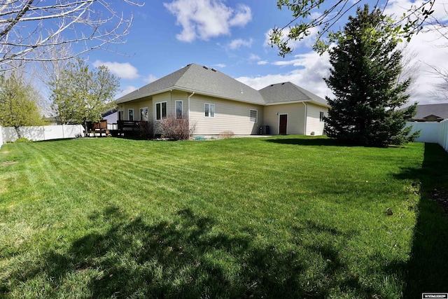 rear view of property with a fenced backyard, a wooden deck, a yard, and central air condition unit