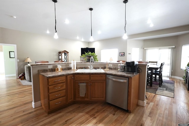 kitchen with a center island with sink, brown cabinets, dishwasher, a sink, and light wood-style flooring